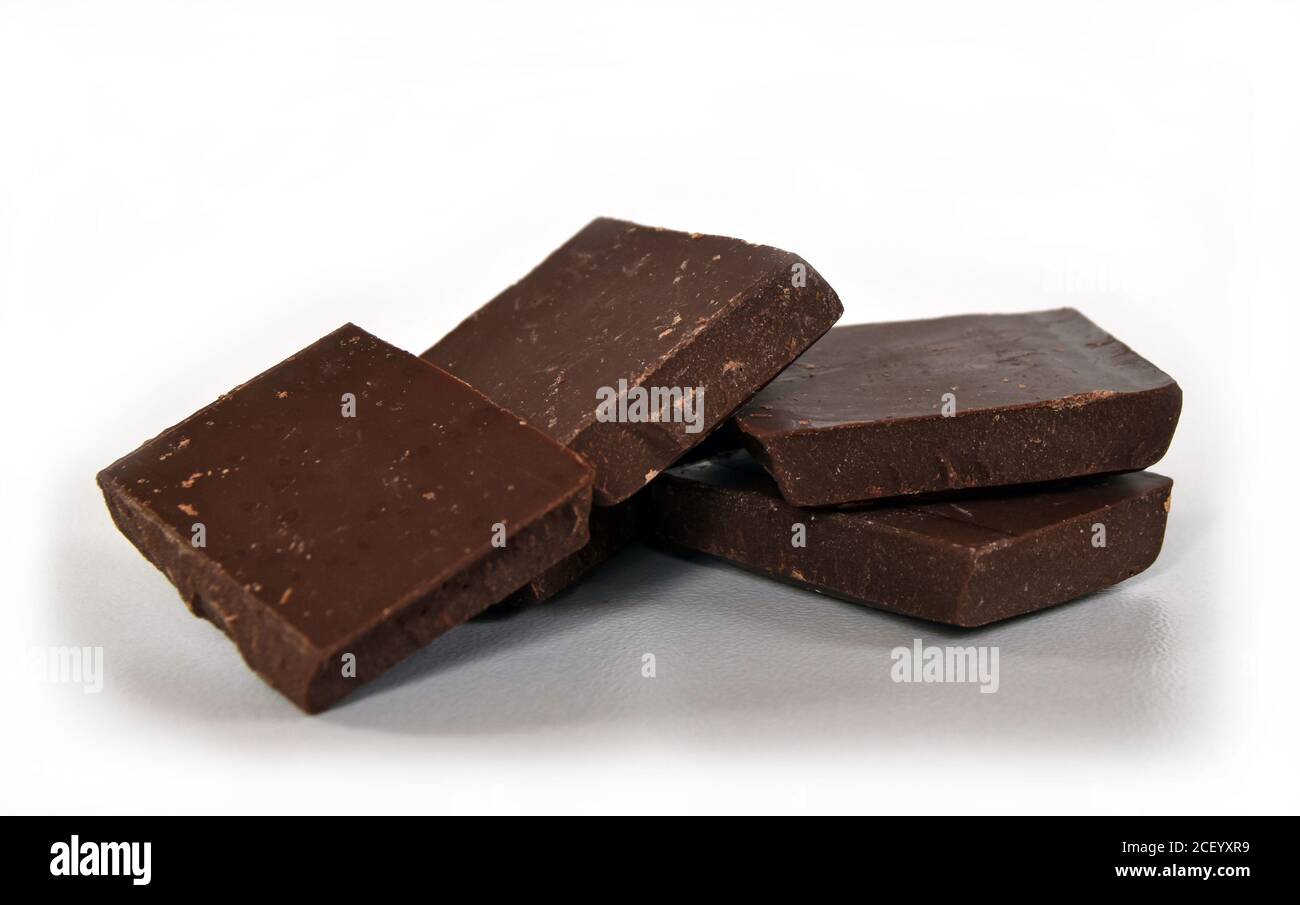 Milch- und dunkle Schokoladenwürfel. Schokoladenstapel auf weißem Hintergrund. Stapel Schokolade. Kleine dunkle Schokoladenstücke. Stockfoto