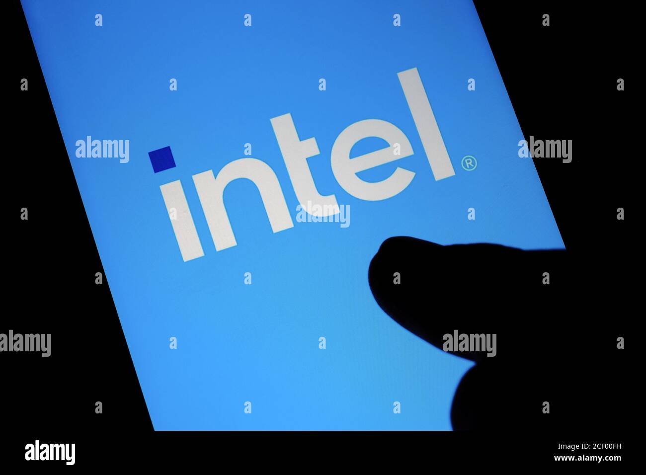 Neues Intel-Logo auf dem Bildschirm und verschwommene Fingerspitzen berühren es in einem dunklen. Intel präsentierte sein umfirmiert Logo o Stockfoto