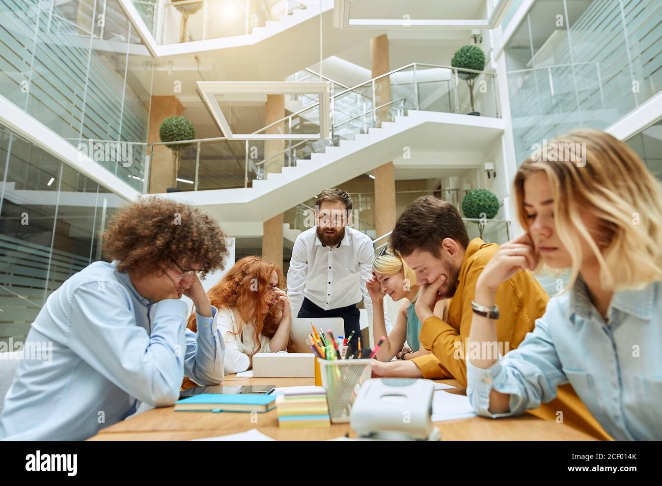 Zwei junge optimistische Mädchen lachen fröhlich über Geschäftstreffen, halten Hände auf Gesichter, verstecken die Augen vor strick-Chef, versuchen, sich zu beruhigen, Arbeitszeitkonzept Stockfoto