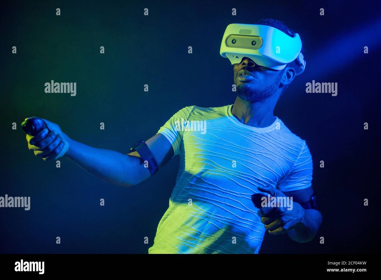 Afrikanische jungen Mann im weißen T-Shirt tragen VR-Headset und das Erleben der Virtuellen Realität. Grün Blau Dual Color Licht auf dunklem Hintergrund. Stockfoto