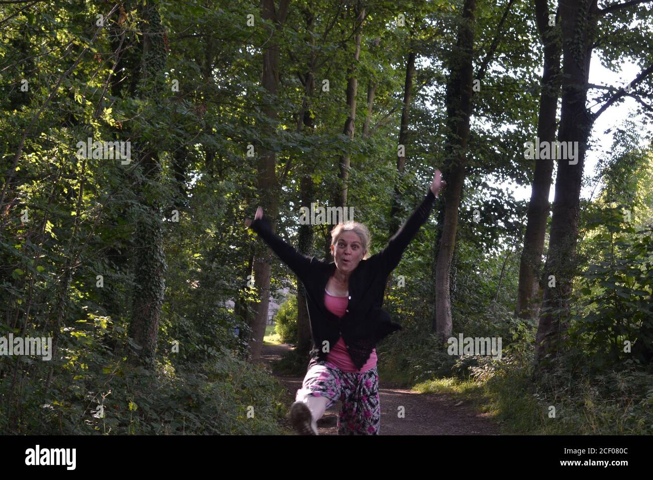 Glückliche springende Dame in Hardwick Hall Wäldern Stockfoto