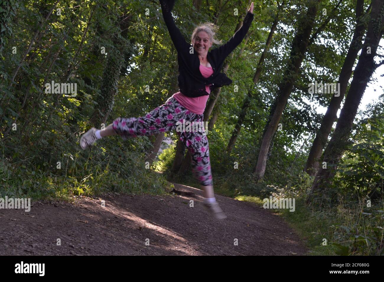 Glückliche springende Dame in Hardwick Hall Wäldern Stockfoto