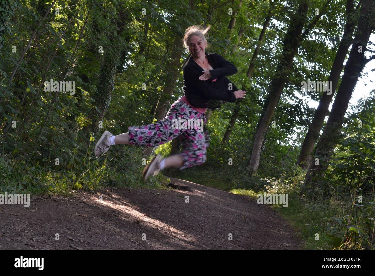 Glückliche springende Dame in Hardwick Hall Wäldern Stockfoto