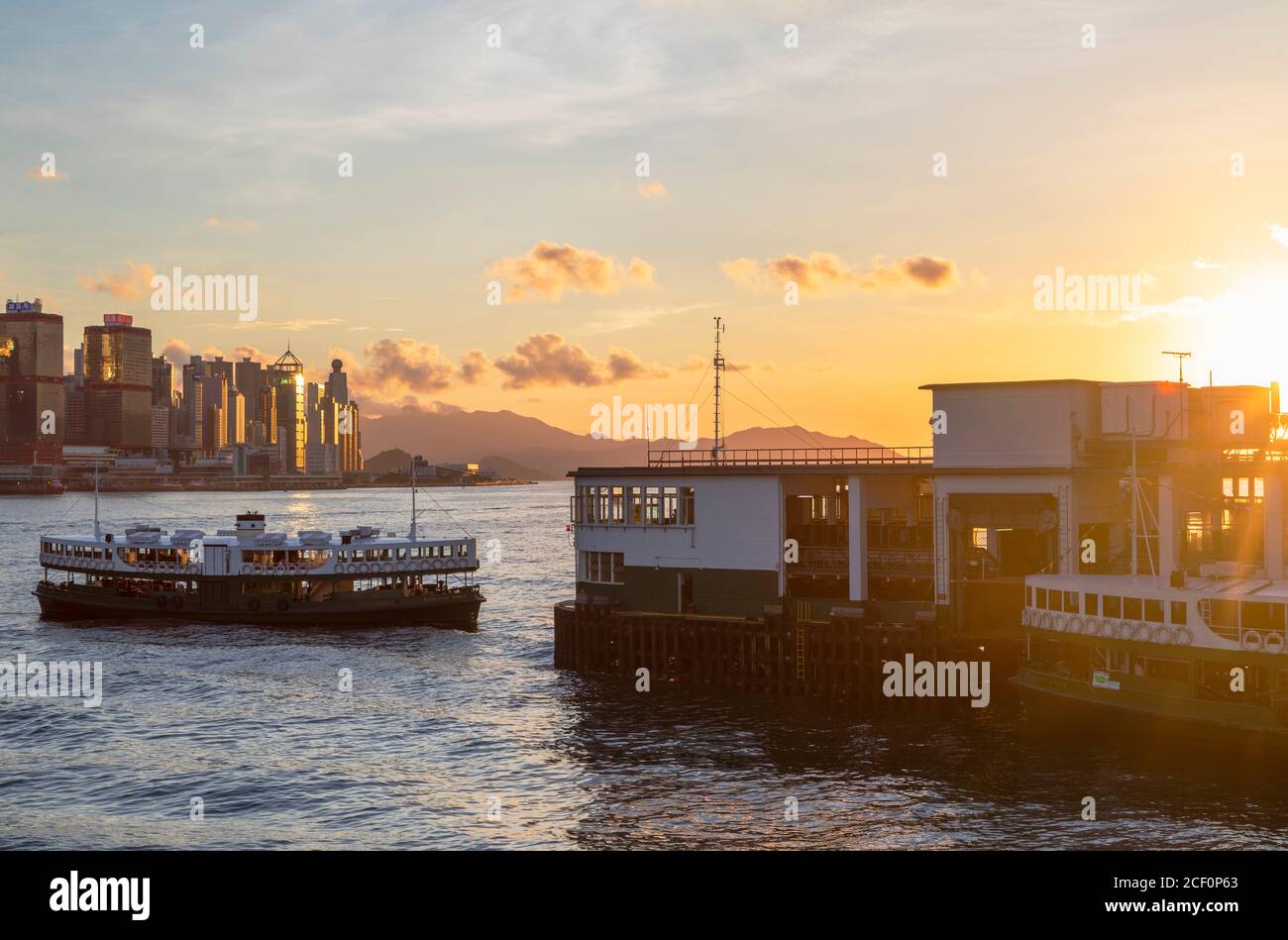 Star Ferry nähert sich dem Star Ferry Pier bei Sonnenuntergang, Tsim Sha Tsui, Kowloon, Hongkong Stockfoto