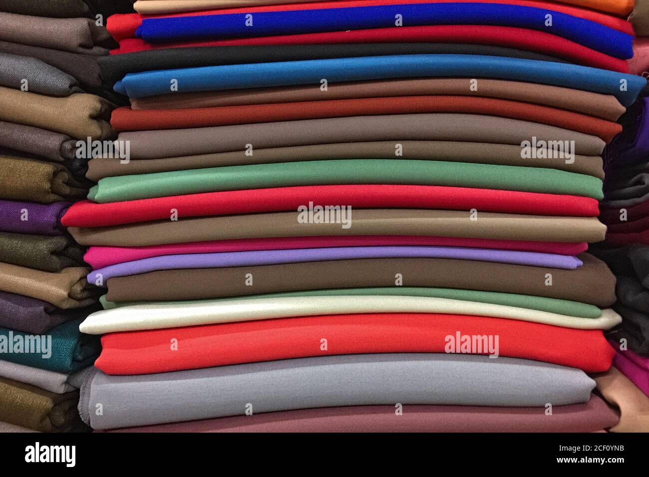 Stapel aus mehrfarbigem Strickmaterial. Textilindustrie, Stoffverkauf. Stockfoto