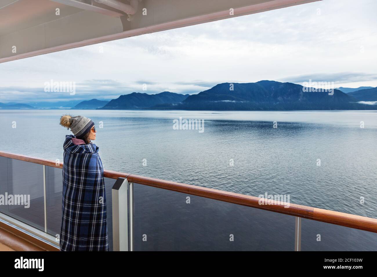 Alaska Kreuzfahrt Reise Luxus Urlaub Frau beobachten Innenpassage landschaftlich Kreuzfahrt Tag auf Balkon Terrasse mit Blick auf die Berge und Naturlandschaft Stockfoto
