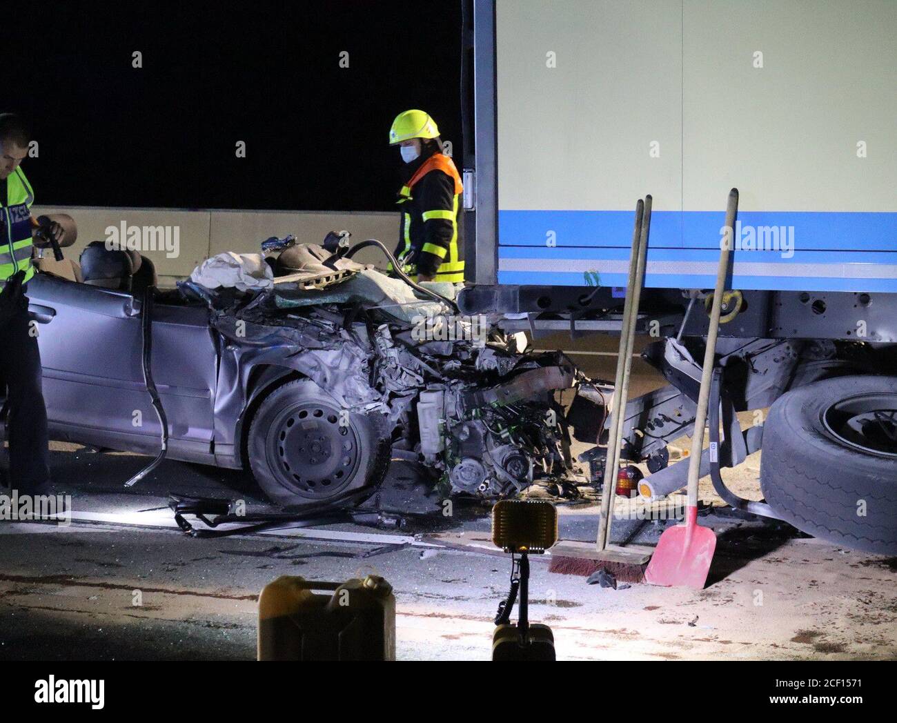 03. September 2020, Hessen, Frankfurt/Main: Polizei und Feuerwehrleute fahren am späten Mittwochabend an einem zerstörten Auto vorbei, mit dem eine Frau auf der Frankfurter A5 in Richtung Darmstadt zwischen dem Frankfurter Kreuz und dem Kreuzweg Zeppelinheim unter einem LKW gefahren wurde und dabei tödlich verletzt wurde. Das Auto musste mit einem Feuerwehrkran herausgezogen und der Fahrer mit einer hydraulischen Rettungsvorrichtung befreit werden. Der Notarzt konnte jedoch nur den Tod feststellen. Die Ursache des Unfalls war zunächst unklar, und die Polizei begann Ermittlungen. Foto: -/5vision.media/dpa Stockfoto