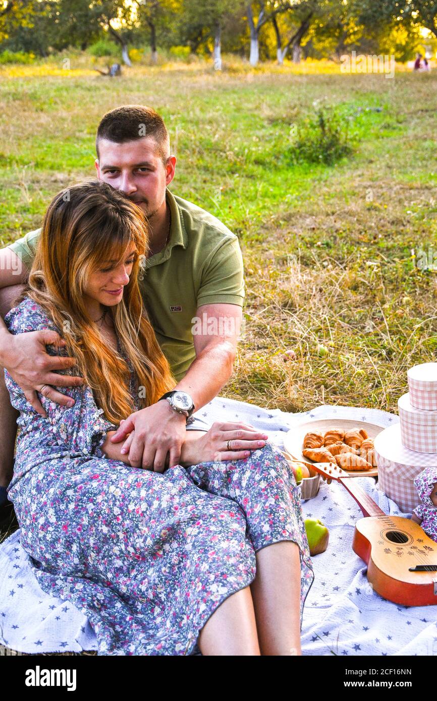 Glückliches junges Paar entspannend und mit Picknick im Park. Friedliche süße  Pärchen genießen Abendessen im Park. Mann und Frau sitzen auf Gras und  umarmen Stockfotografie - Alamy