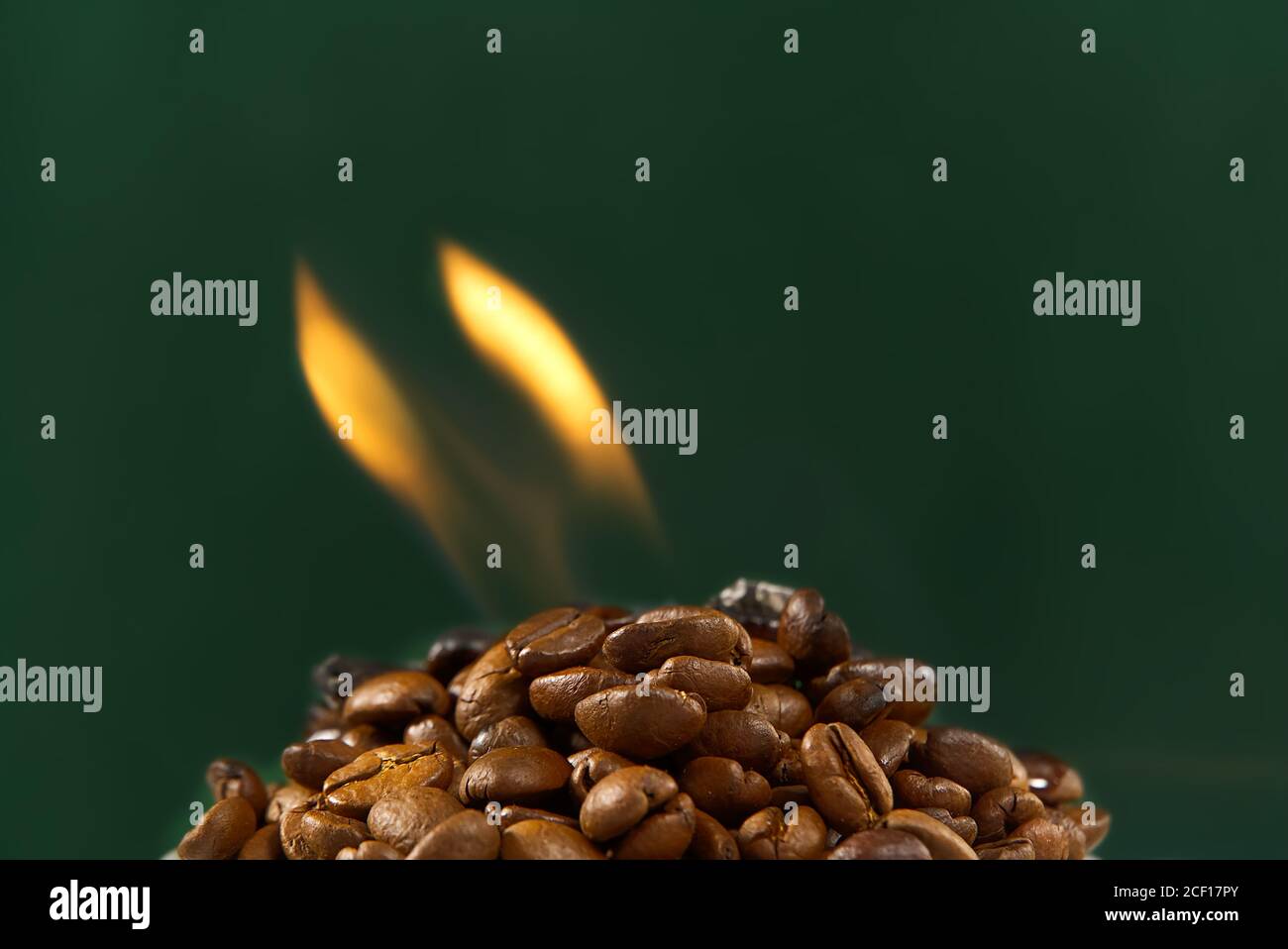 Internationaler Tag des Kaffee-Konzept. Nahaufnahme Stapel von Kaffeebohnen auf grünem Hintergrund mit Feuer auf der Oberseite. Stockfoto
