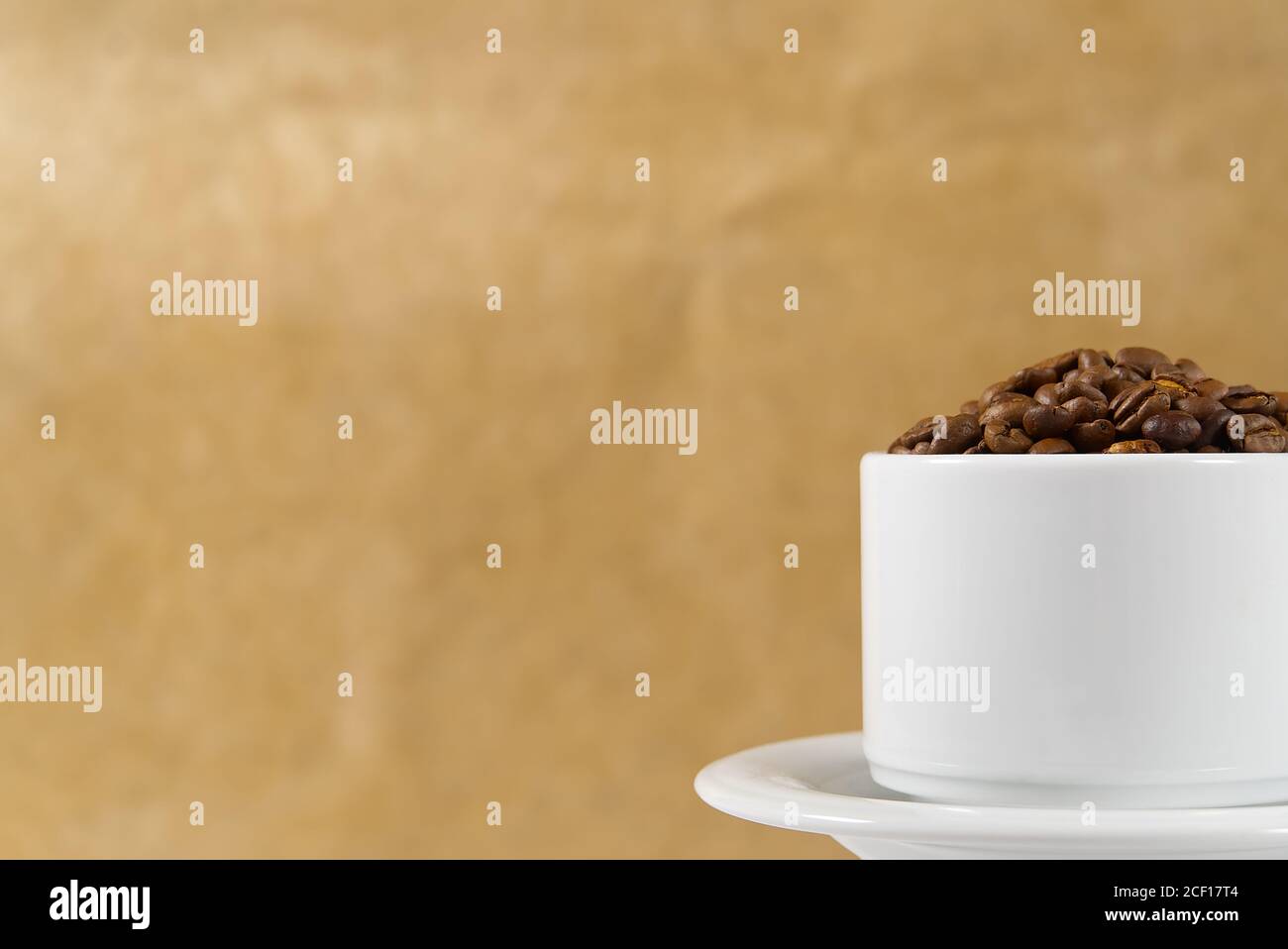 Internationaler Tag des Kaffees Konzept. Nahaufnahme weiße Kaffeetasse voller Kaffeebohnen auf beigem Hintergrund. Stockfoto