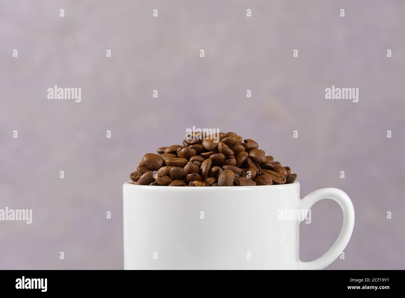 Internationaler Tag des Kaffees Konzept. Nahaufnahme weiße Kaffeetasse voller Kaffeebohnen auf alten Rosen Hintergrund. Stockfoto