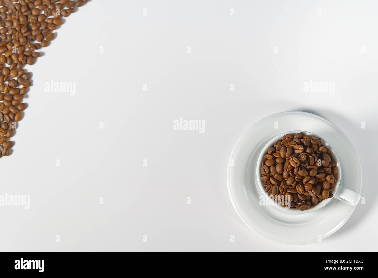 Kaffeebohnen in weißer Tasse, Nahaufnahme. Weiße Kaffeetasse mit Kaffeesamen auf weißem Hintergrund. Konzept für den Internationalen Tag des Kaffees. Stockfoto