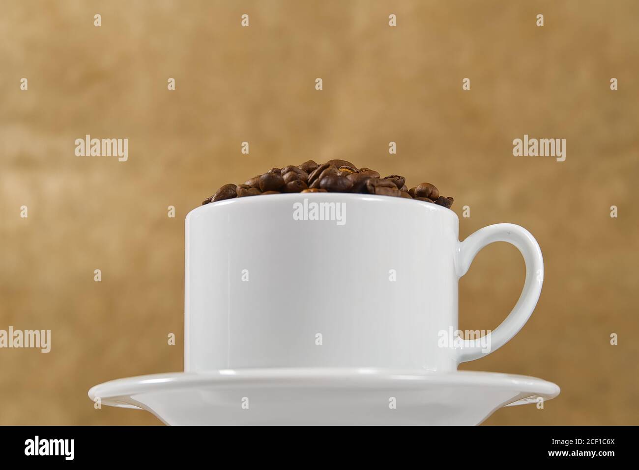 Internationaler Tag des Kaffees Konzept. Nahaufnahme weiße Kaffeetasse voller Kaffeebohnen auf beigem Hintergrund. Stockfoto