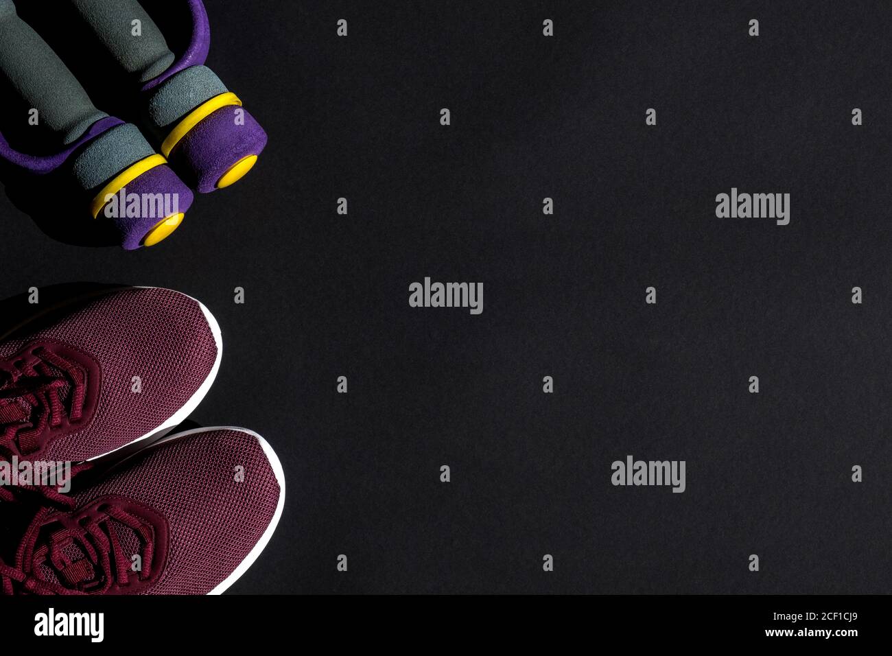 Sneaker und Hanteln für das Training zu Hause und im Fitnessstudio auf dunklem Hintergrund. Körperpflegekonzept, aktiver Lebensstil. Draufsicht. Leerzeichen für Text. Stockfoto