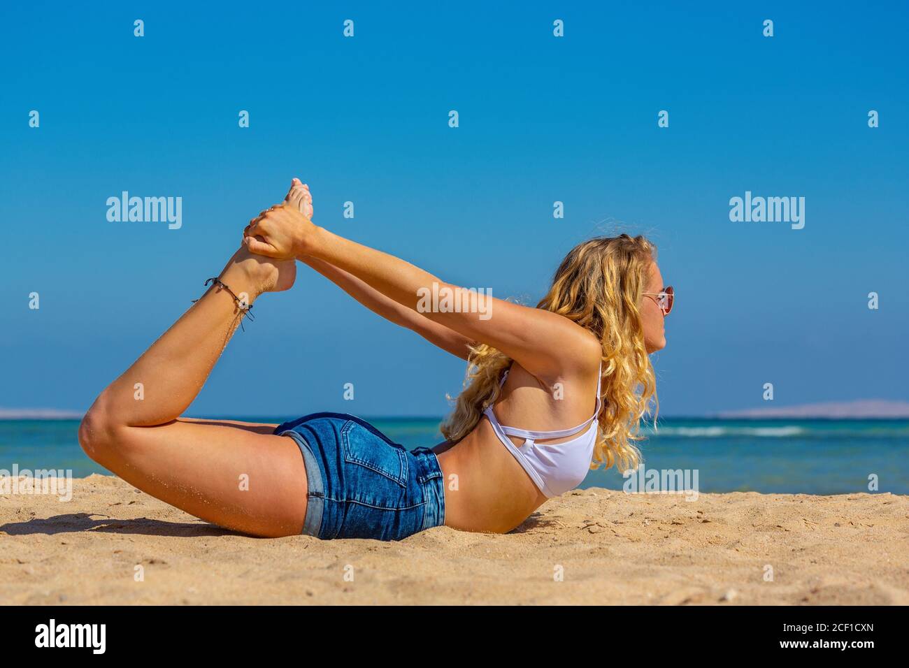 Junge blonde kaukasische Frau beugt sich rückwärts auf ägyptischen Strand Stockfoto