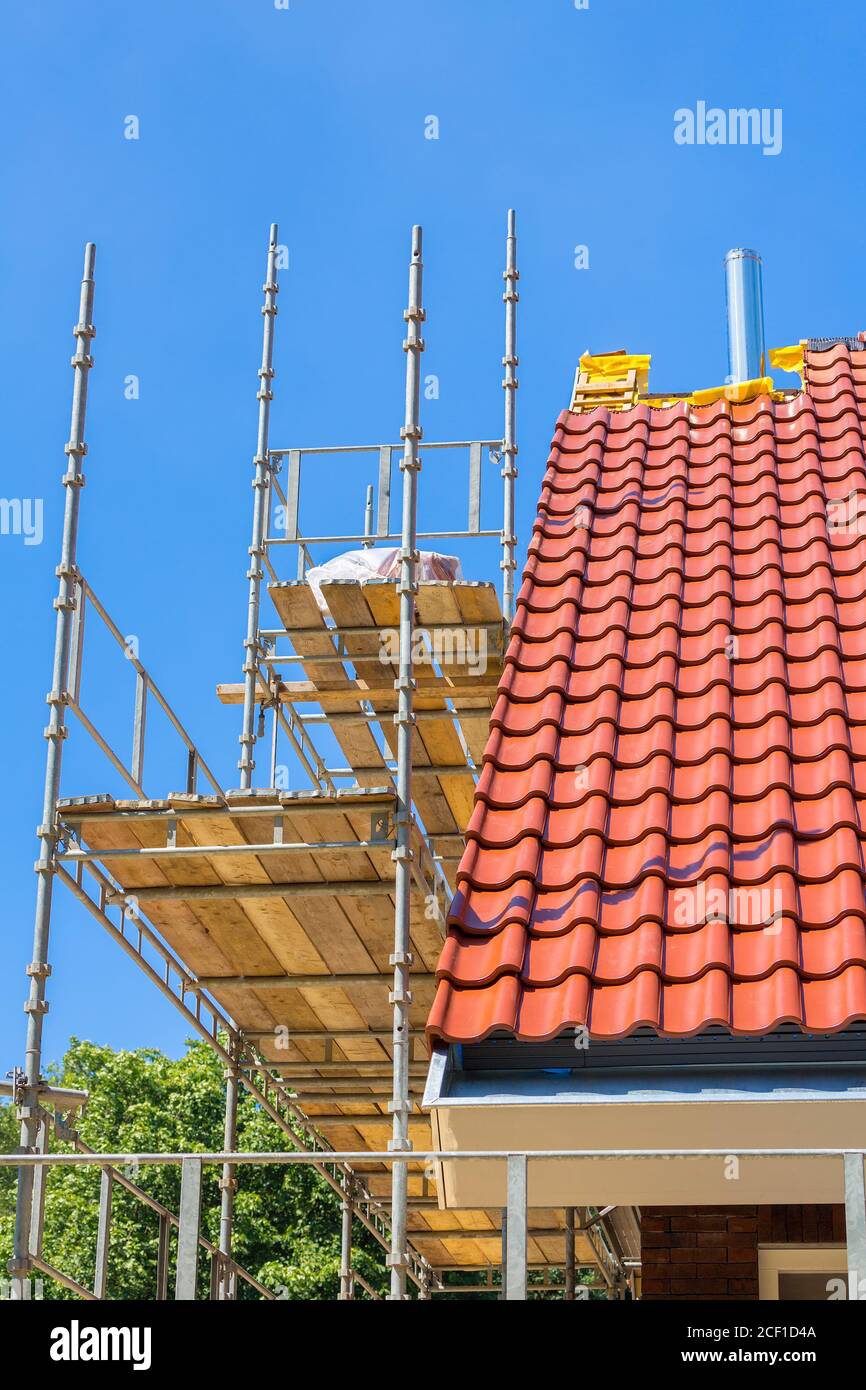 Neue Dachziegel auf Haus mit Gerüsten und blauen Himmel Stockfoto