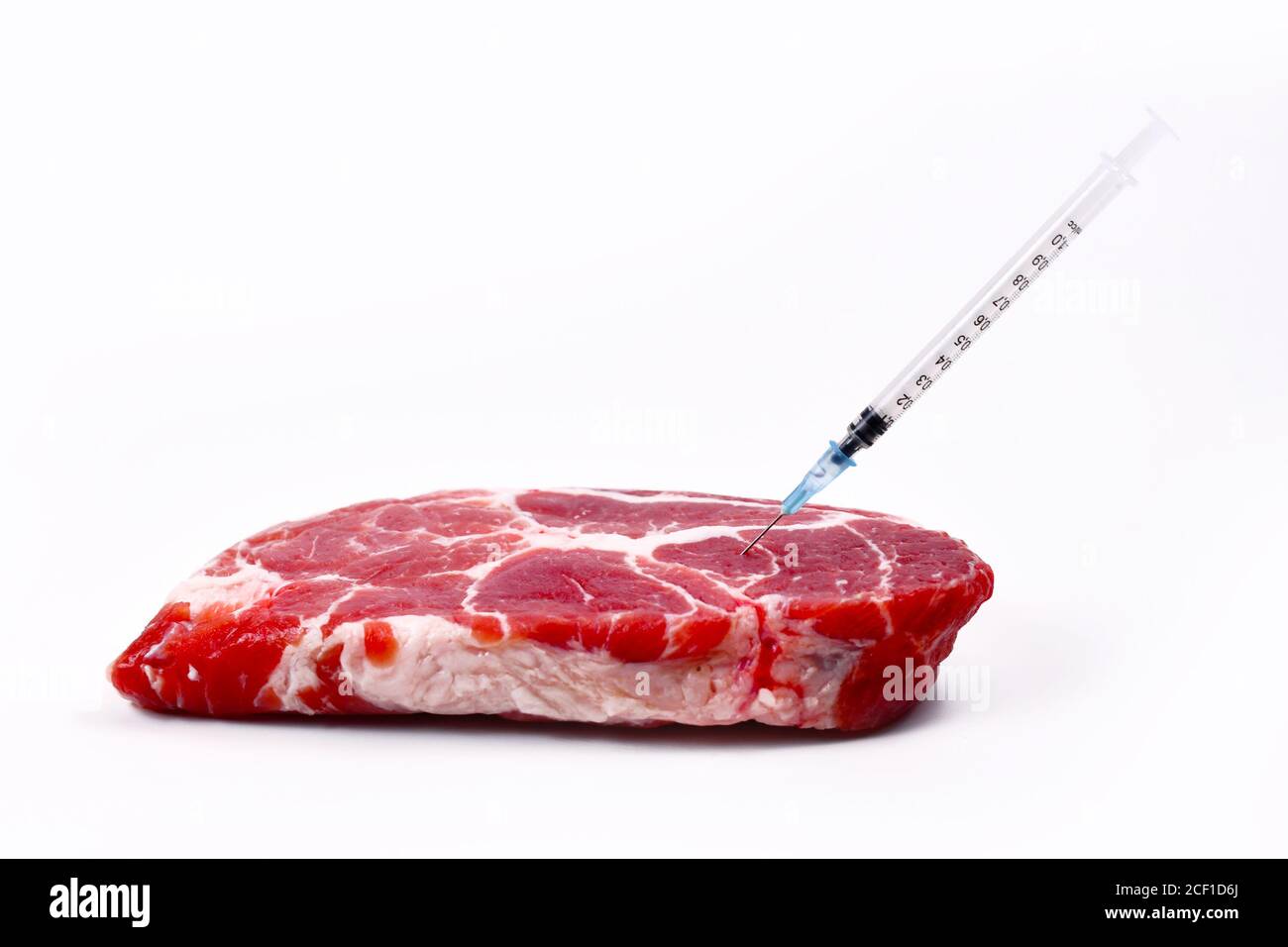 Konzept für gentechnisch veränderte Tiere oder Antibiotika und Arzneimittelrückstände In Lebensmitteln mit rohem rotem Fleisch mit eingespritzter Spritze Stockfoto