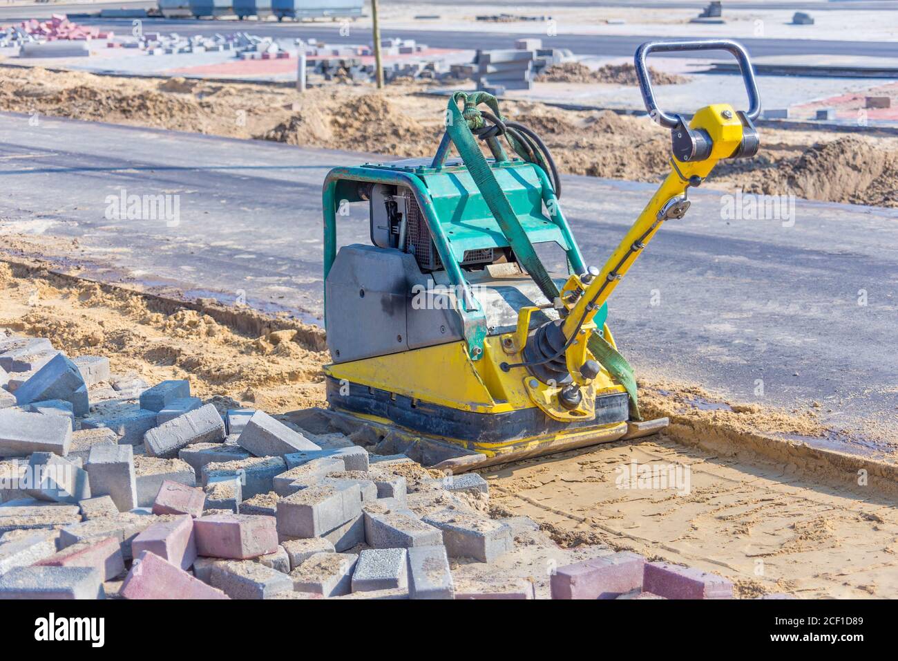 Vibrierende Maschine auf Sand neben der neuen Straße in der Straße Konstruktion Stockfoto