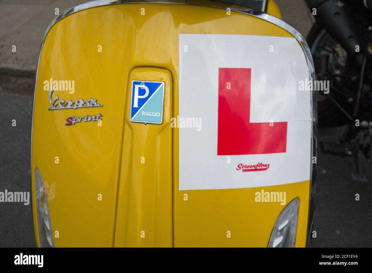 L Teller auf einer ikonischen, gelben Vespa Piaggio Sprint Stockfoto