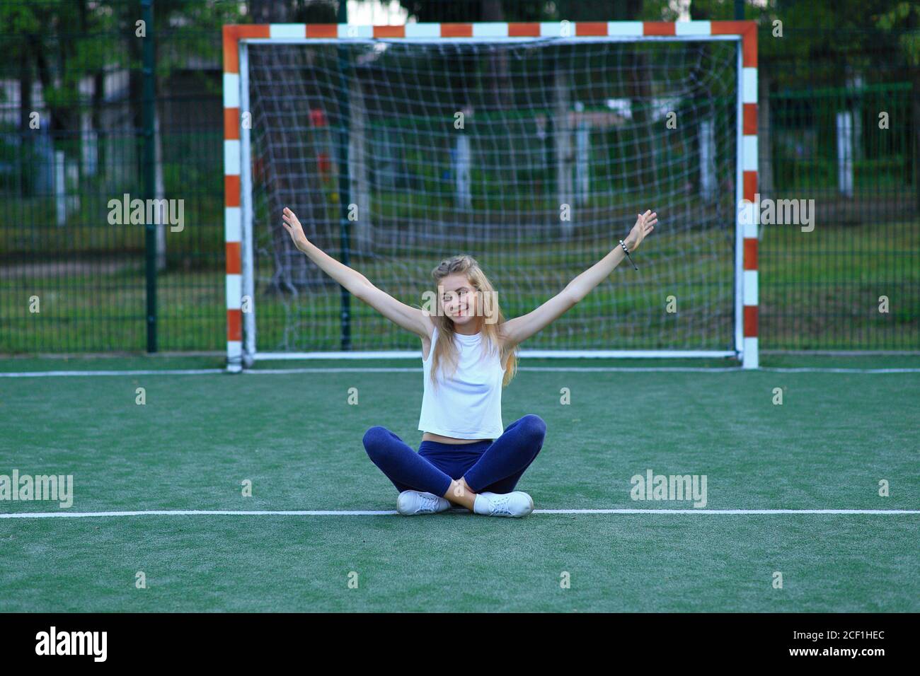 Ein Mädchen posiert in der Nähe eines Fußballtor auf einem Sportplatz. Stockfoto