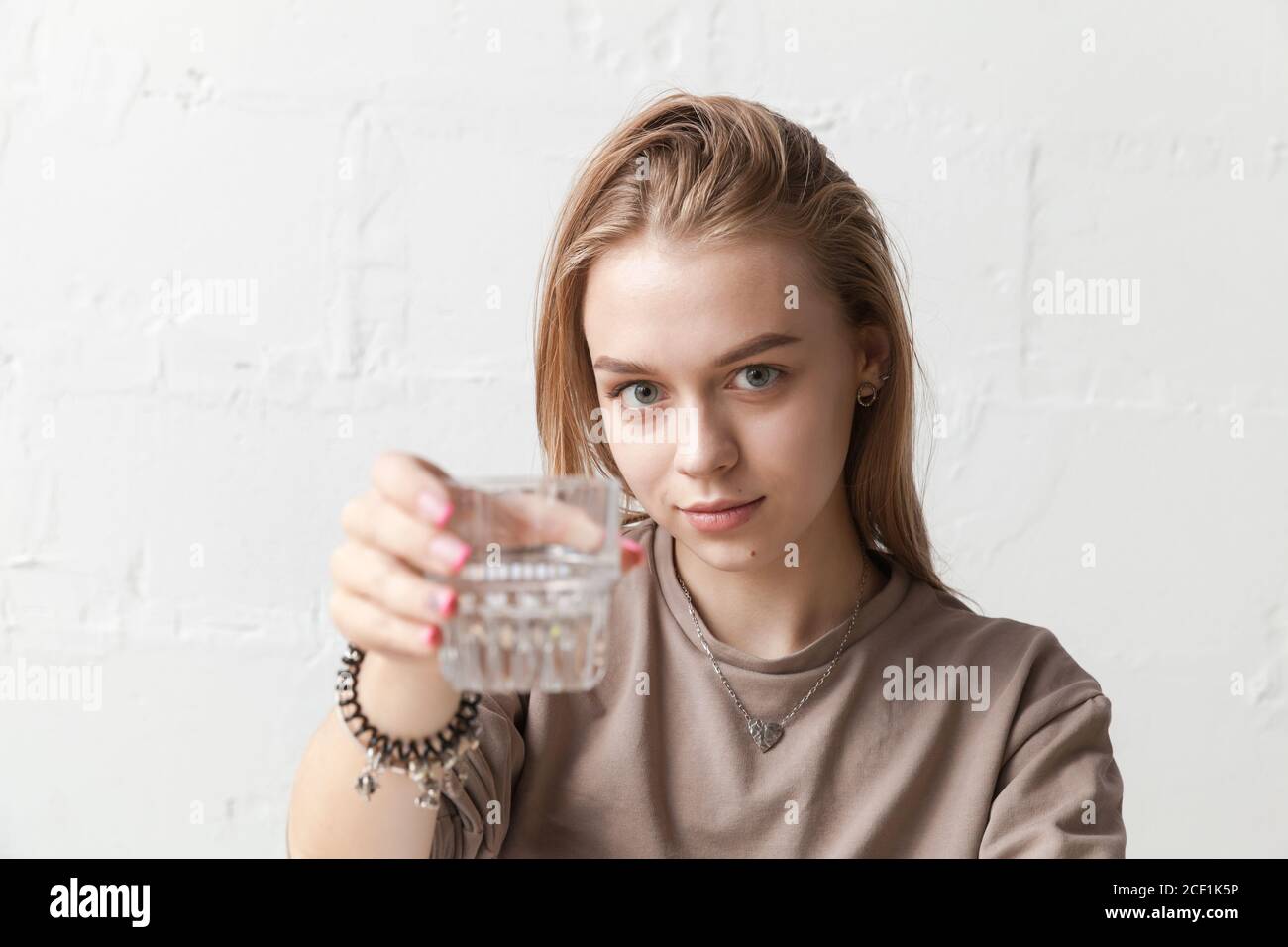 Junge blonde Mädchen hält ein Glas Wasser, Nahaufnahme Foto mit selektiven weichen Fokus auf Gesicht Stockfoto