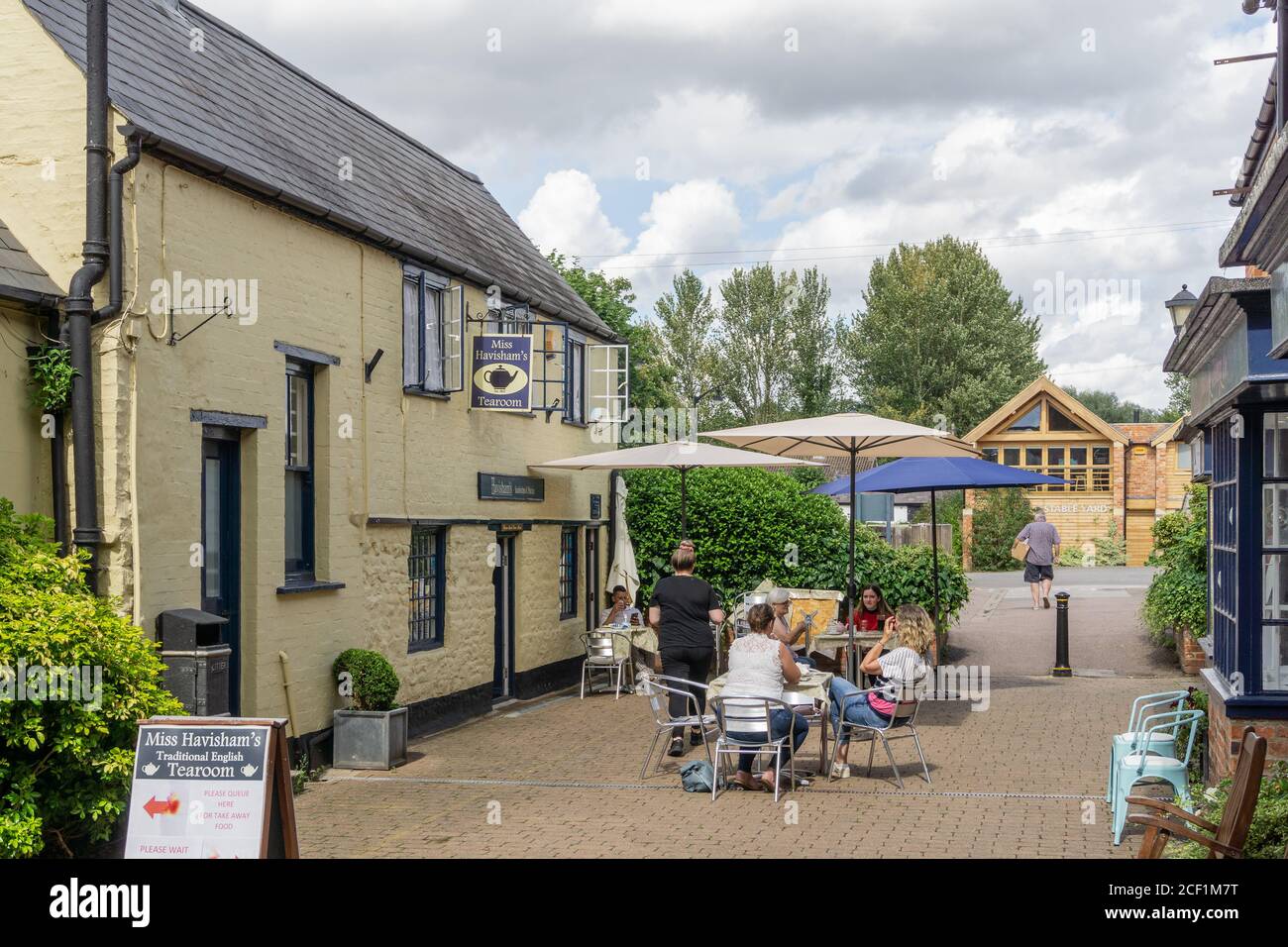 Gäste genießen den Nachmittagstee im Miss Havisham's Tearoom, einem traditionellen Café in einem malerischen Innenhof neben der High Street, Stony Stratford, Großbritannien Stockfoto