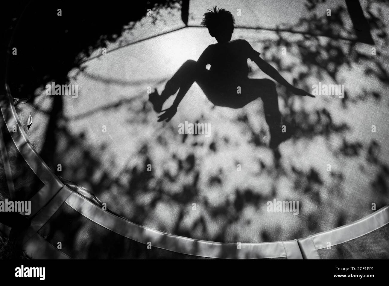 Schatten des Jungen springen auf sonnigem Trampolin Stockfoto