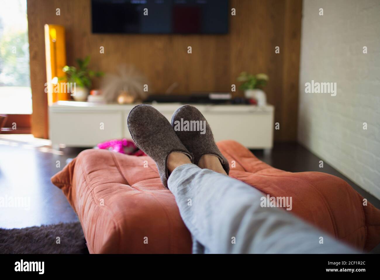 POV Frau in Pantoffeln entspannend mit den Füßen im Leben Zimmer Stockfoto