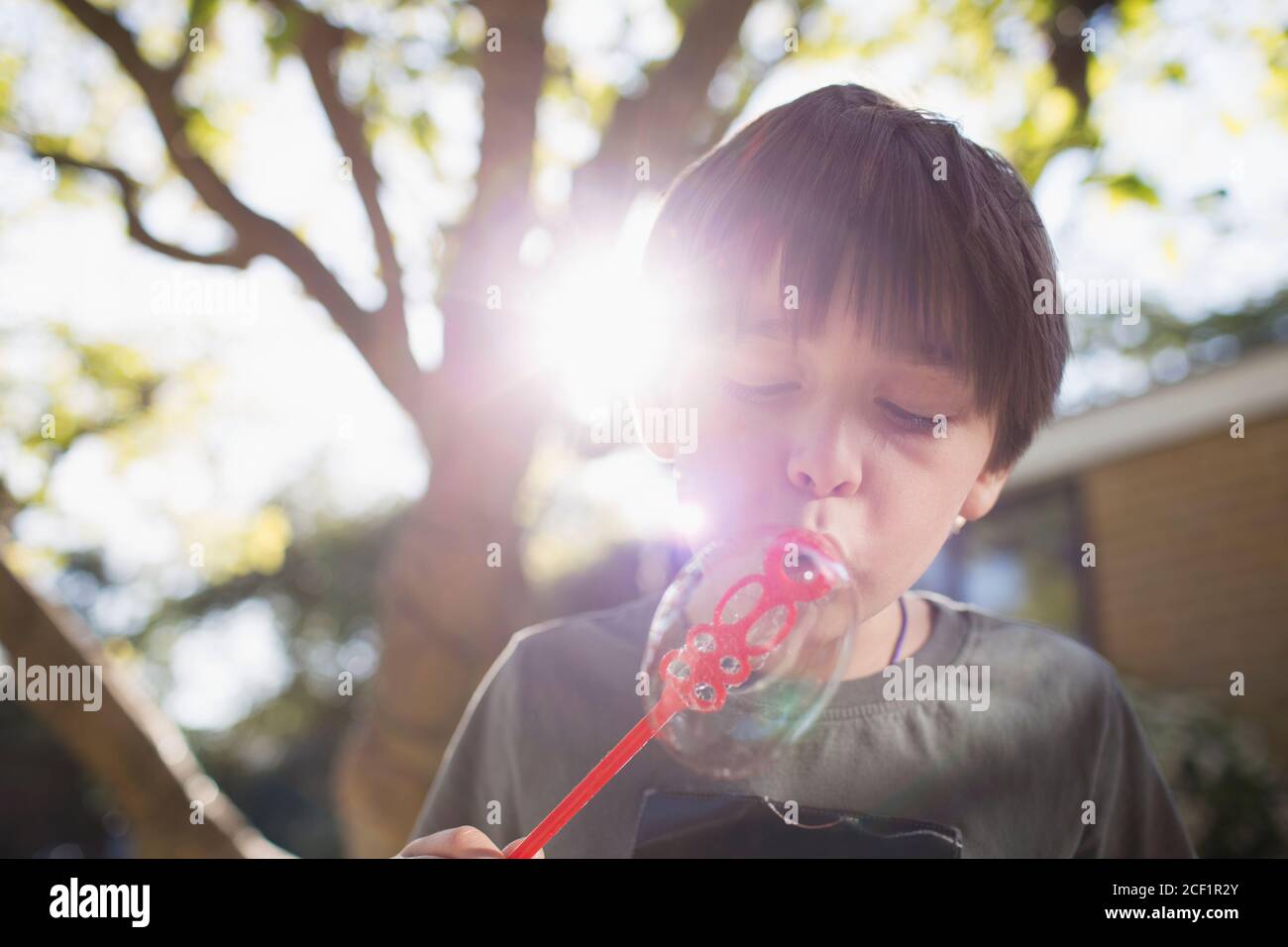 Junge blasen Blasen im sonnigen Hinterhof Stockfoto