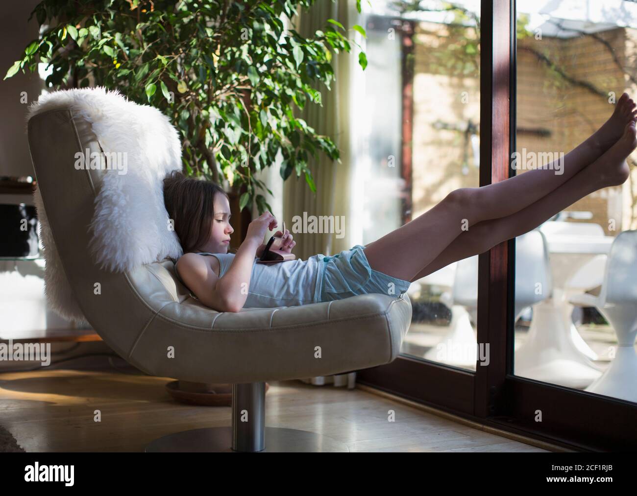 Mädchen mit Smartphone entspannend mit den Füßen im Leben Zimmer Stockfoto