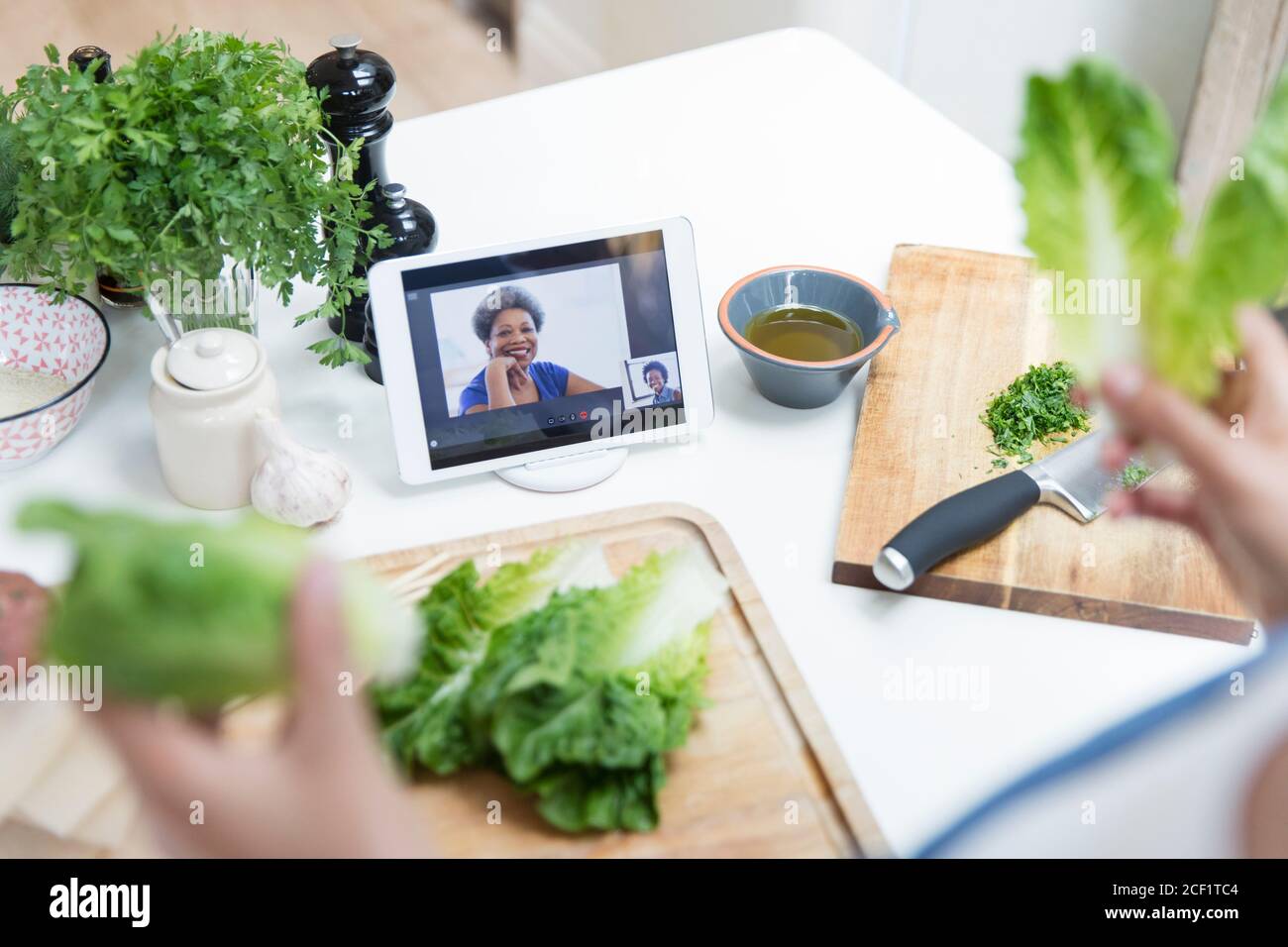 Frau mit Salat Kochen und Video-Chat mit Freunden in Küche Stockfoto