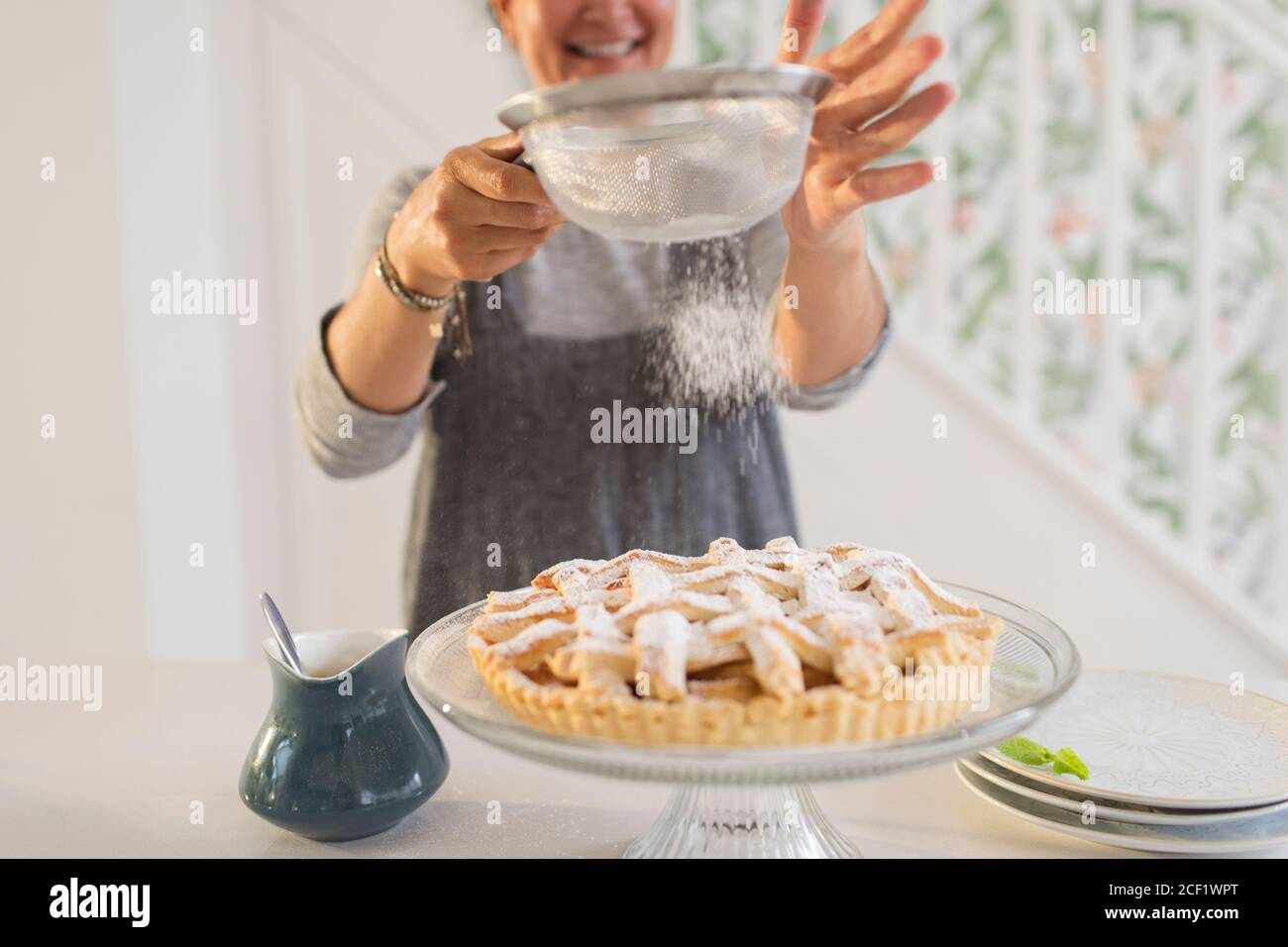 Frau streut frisch gebackenen Apfelkuchen mit Puderzucker Stockfoto