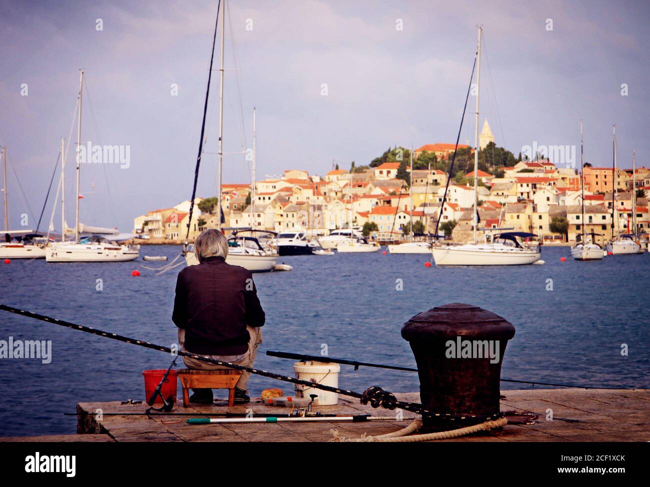 Kroatien - Sommeruntergang, der Mann fischt von einem Pier vor der Halbinsel Primosten Stockfoto