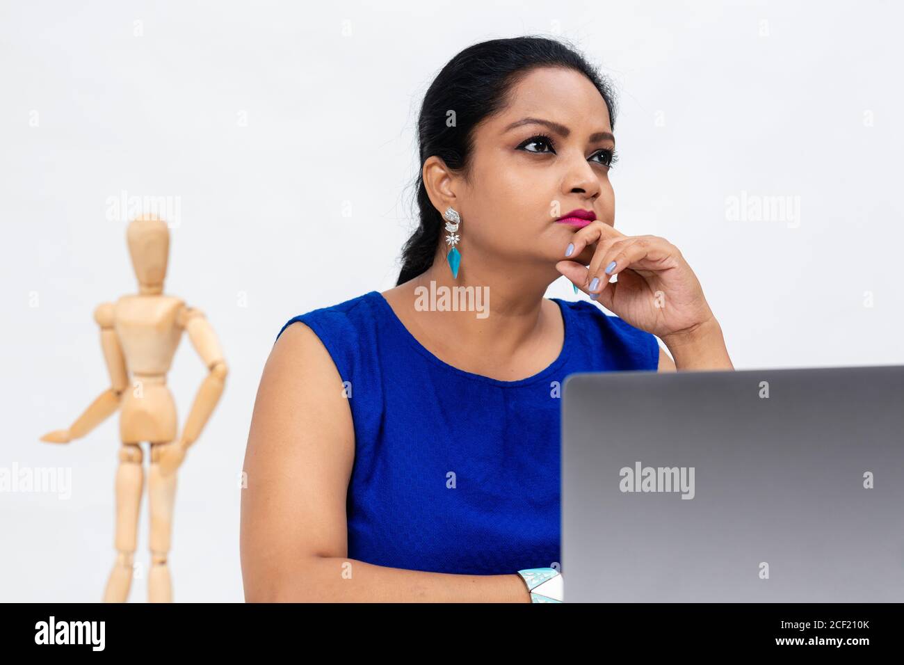 Hübsche indische Frau am Tisch, Freiberufler, Fernarbeit, Arbeit zu Hause, Online-Bildung, Büroarbeit zu Hause, in Gedanken verloren. Stockfoto