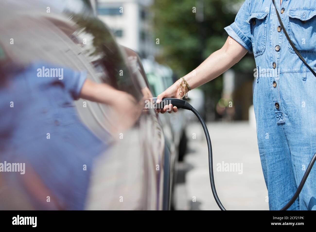 Frau lädt Elektroauto Stockfoto