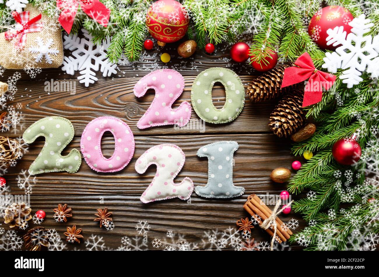 Bunt genähte Ziffern 2020 2021 aus Polkadot Stoff mit Weihnachtsdekorationen flach legen auf Holzhintergrund. Stockfoto
