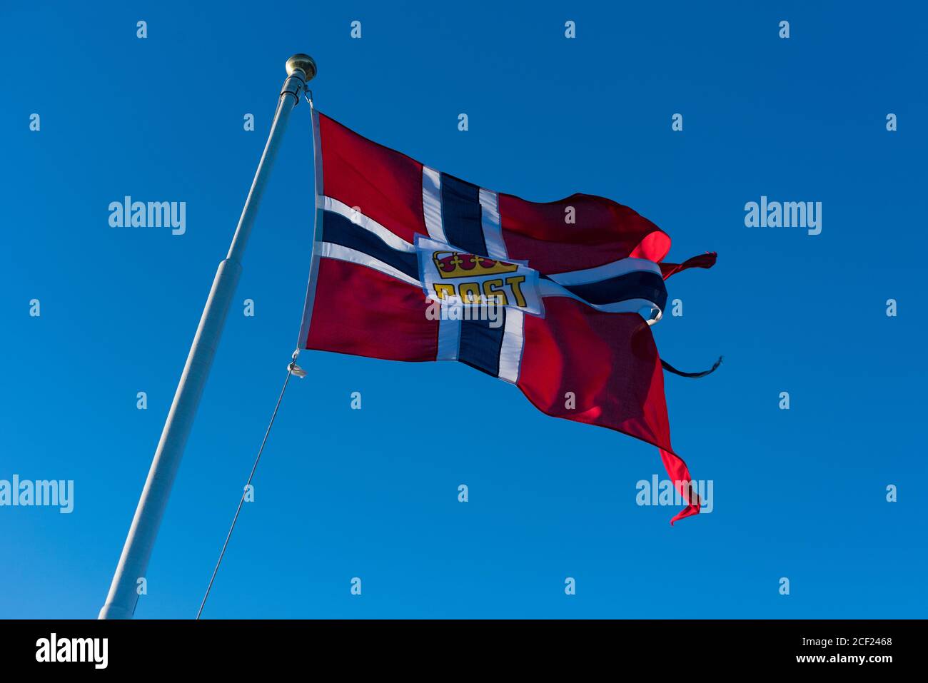 Norwegische Post oder Post Flagge gehisst auf Post von Postboat Winken im Wind mit blauem Himmel im Hintergrund Stockfoto