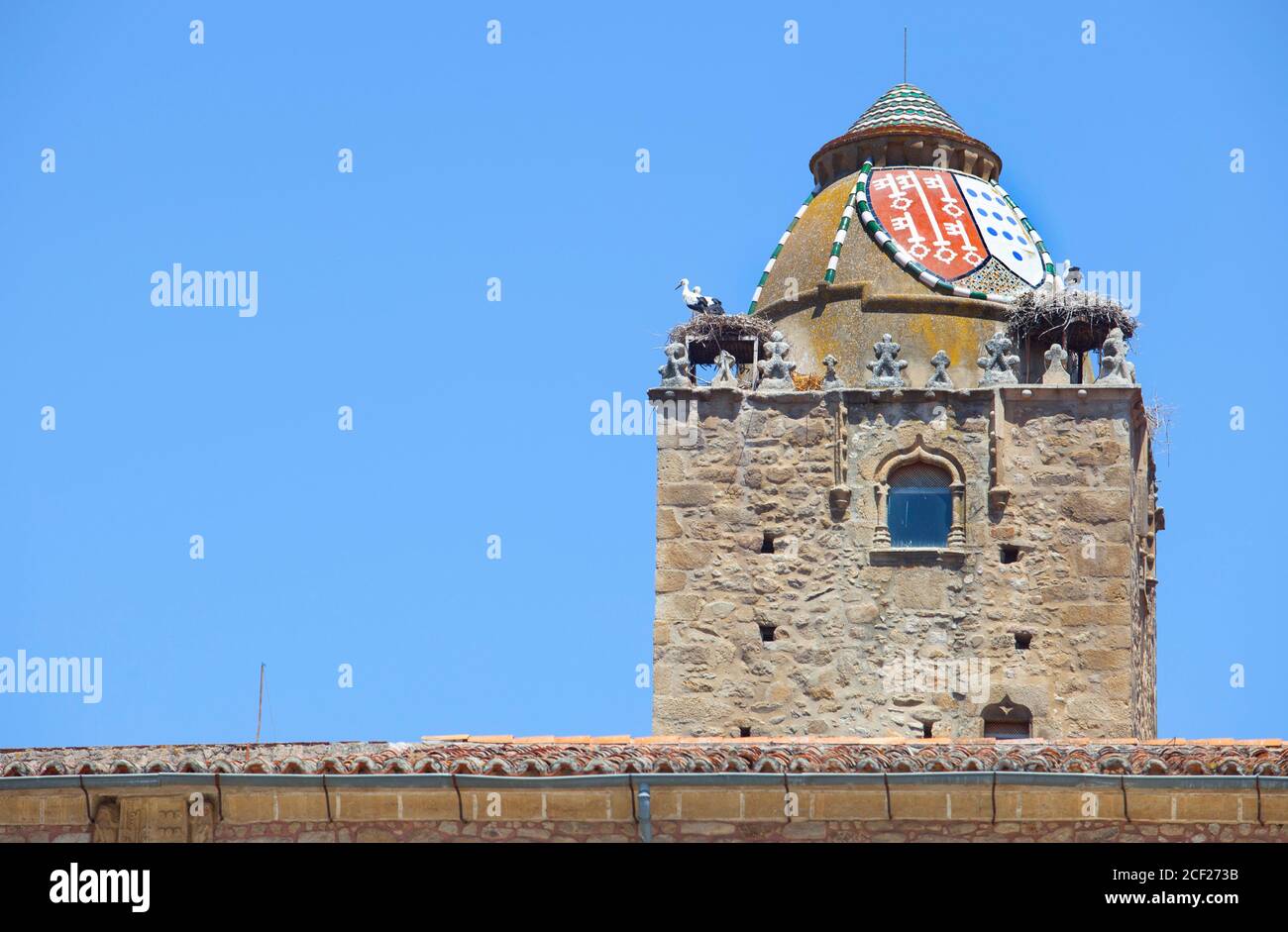 Alfiler Turm, ein gotischer Glockenturm aus dem 14. Jahrhundert, geschmückt mit verglasten Dachziegeln und beliebter Nistplatz für Störche, Trujillo, Spanien. Stockfoto