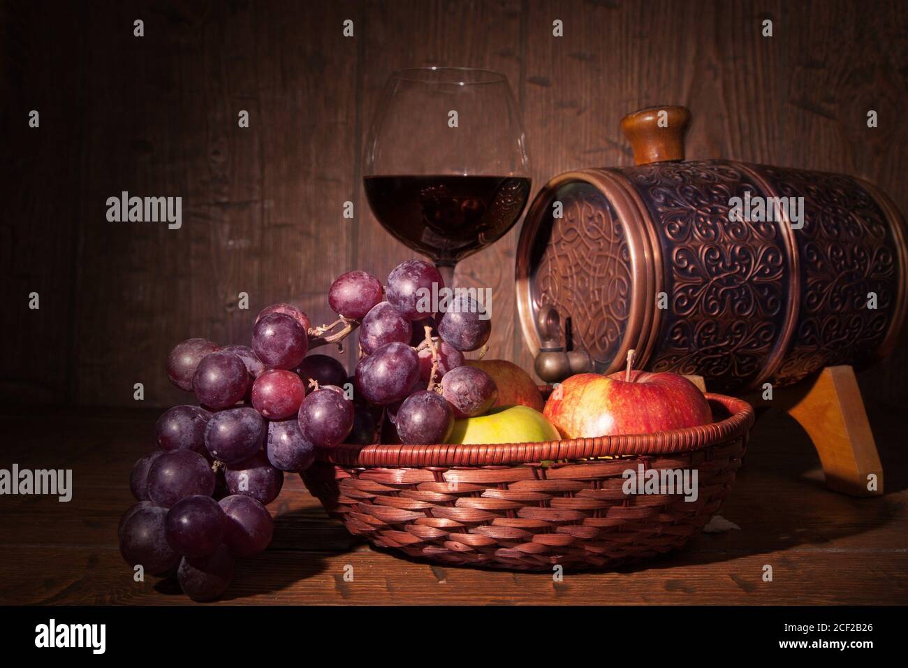 Glas Rotwein und Fass auf rustikalem Holztisch. Stockfoto