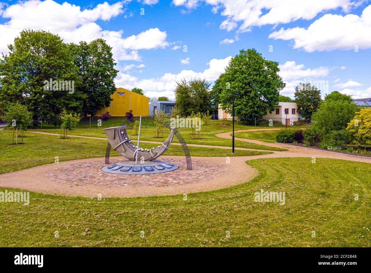 Stadtbild der kleinen lettischen Stadt Auce, Stadtpark mit stilisierter Sonnenuhr in Form eines Posthorns Stockfoto