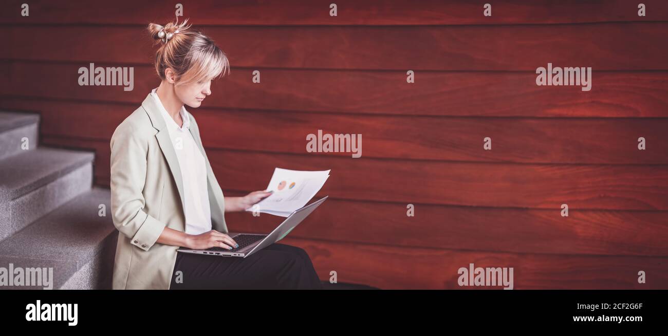 Junge Frau mit Laptop sitzt auf der Treppe Stockfoto