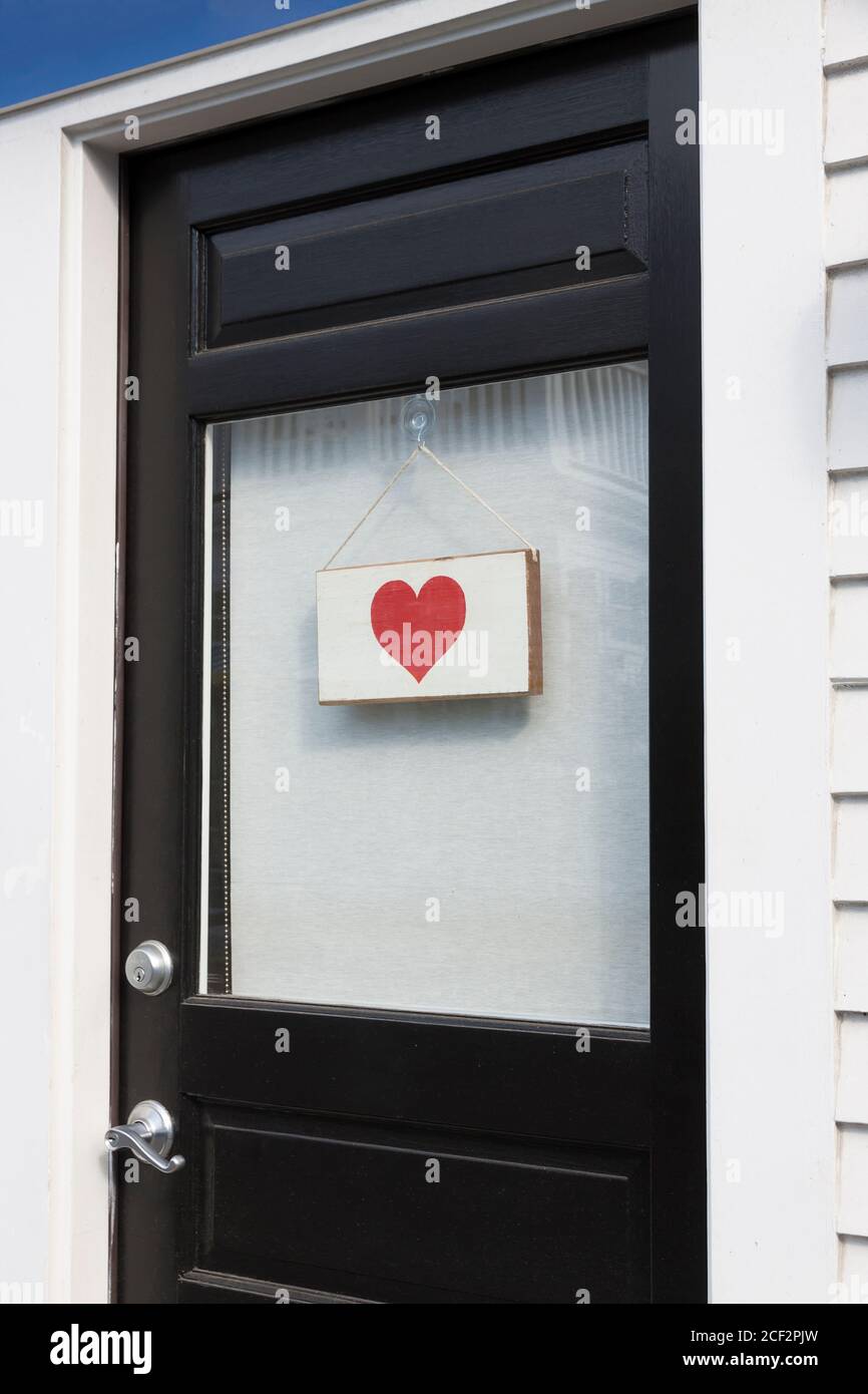 Rotes Herz hängt an einer Haustür. Stockfoto
