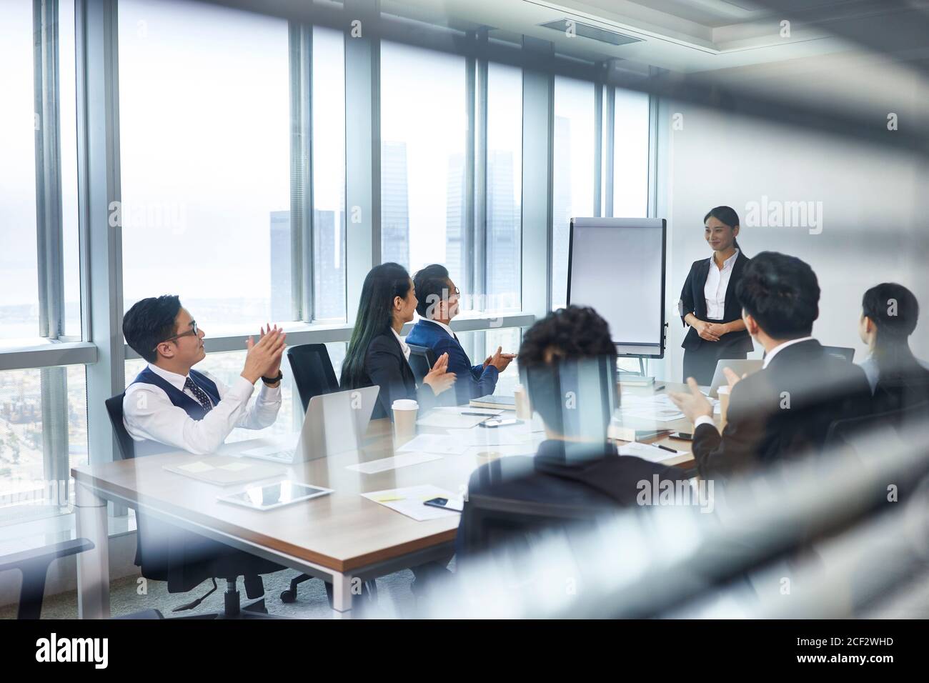 asiatischer neuer Mitarbeiter, der sich während der Mitarbeiterbesprechung in der Konferenz vorstellt Zimmer Stockfoto