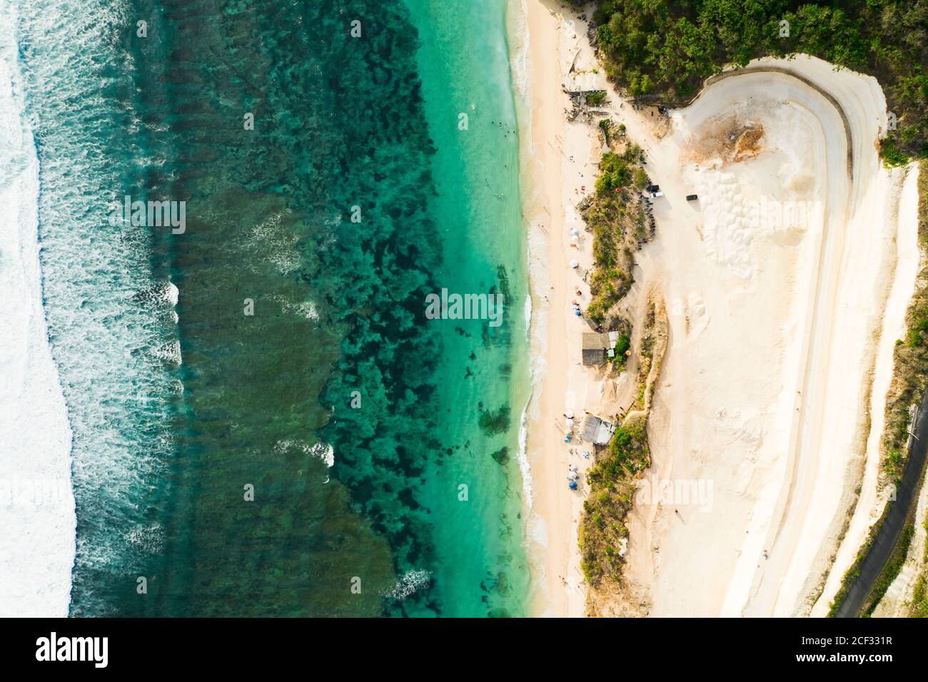 Blick von oben, atemberaubende Luftaufnahme eines wunderschönen Strandes, der während des Sonnenuntergangs von einem türkisfarbenen Meer umspült wird, Melasti Beach, South Bali, Indonesien. Stockfoto