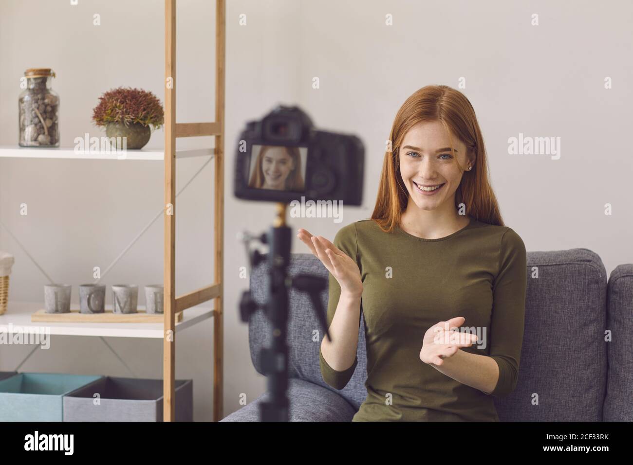 Blogger Vlogger Mädchen spricht mit der Kamera, während auf einem Sofa in einem Raum zu Hause sitzen. Stockfoto