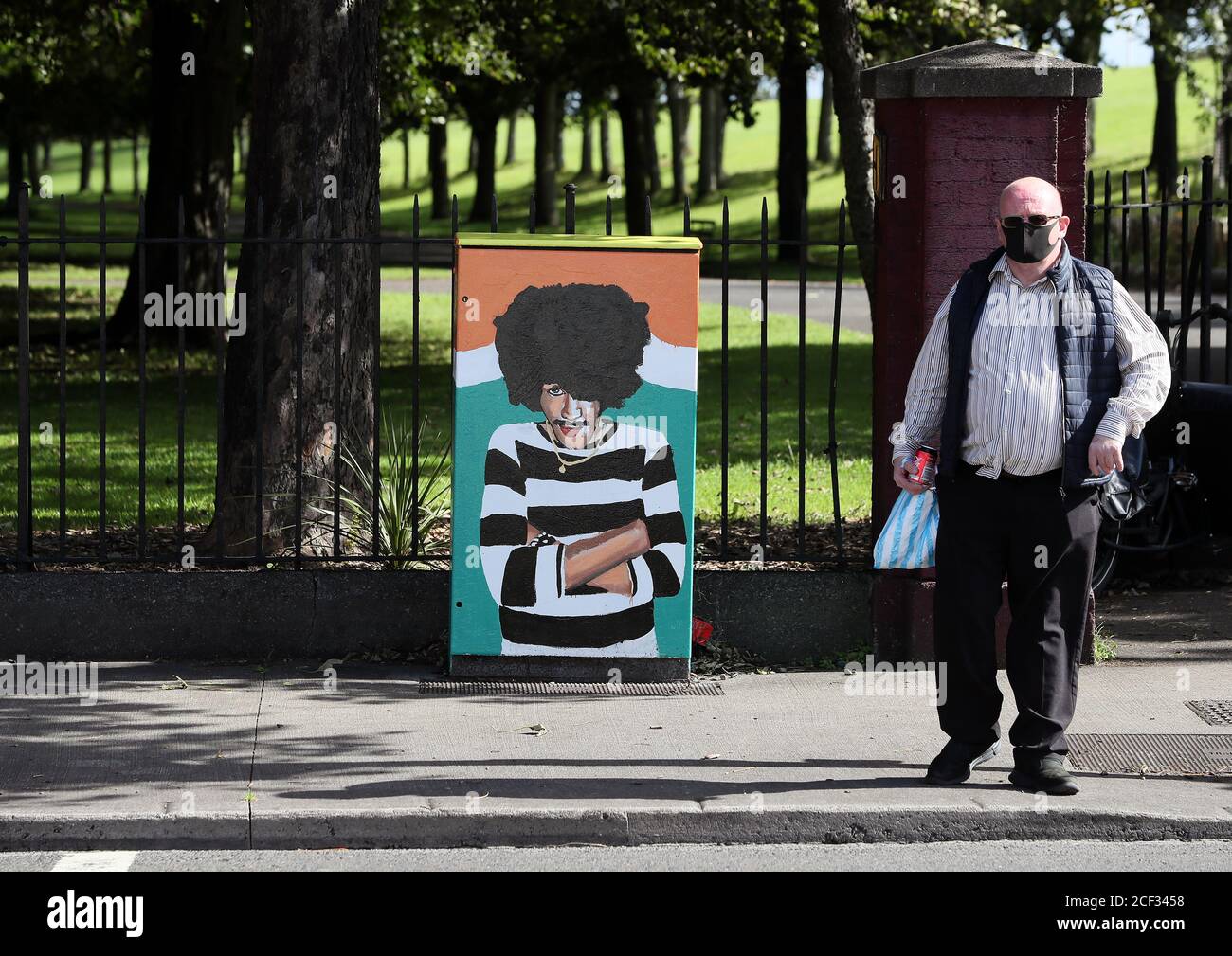 Ein Mann passiert ein neues Wandgemälde von Thin Lizzy Frontmann Phil Lynott, das von der Künstlerin Aine Macken mit dem Titel "One of Our Own" betitelt wurde und auf einer Strombox in seiner Heimatstadt Crumlin in Dublin gemalt wurde. Stockfoto