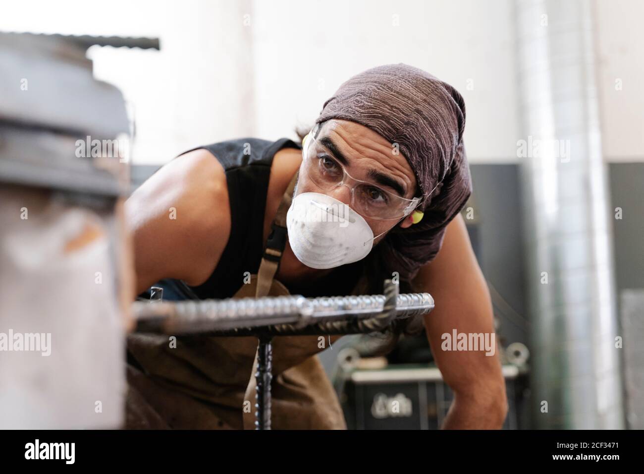 Männliche Schmied in Schutzmaske in der Werkstatt tun Metallarbeiten Stockfoto