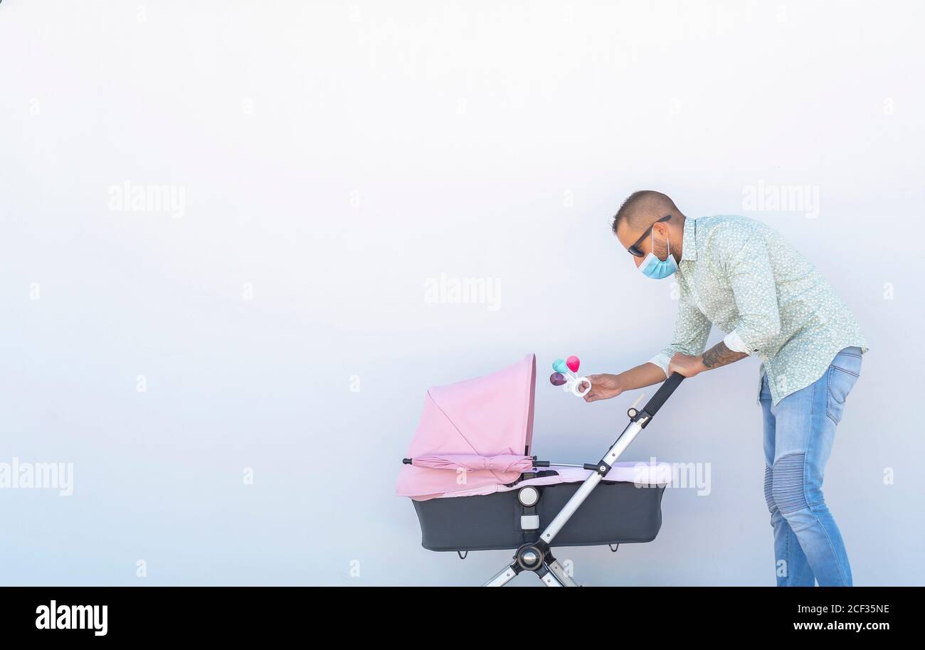 Vater spielt mit der Rassel mit seinem Baby in seinem Kinderwagen Stockfoto