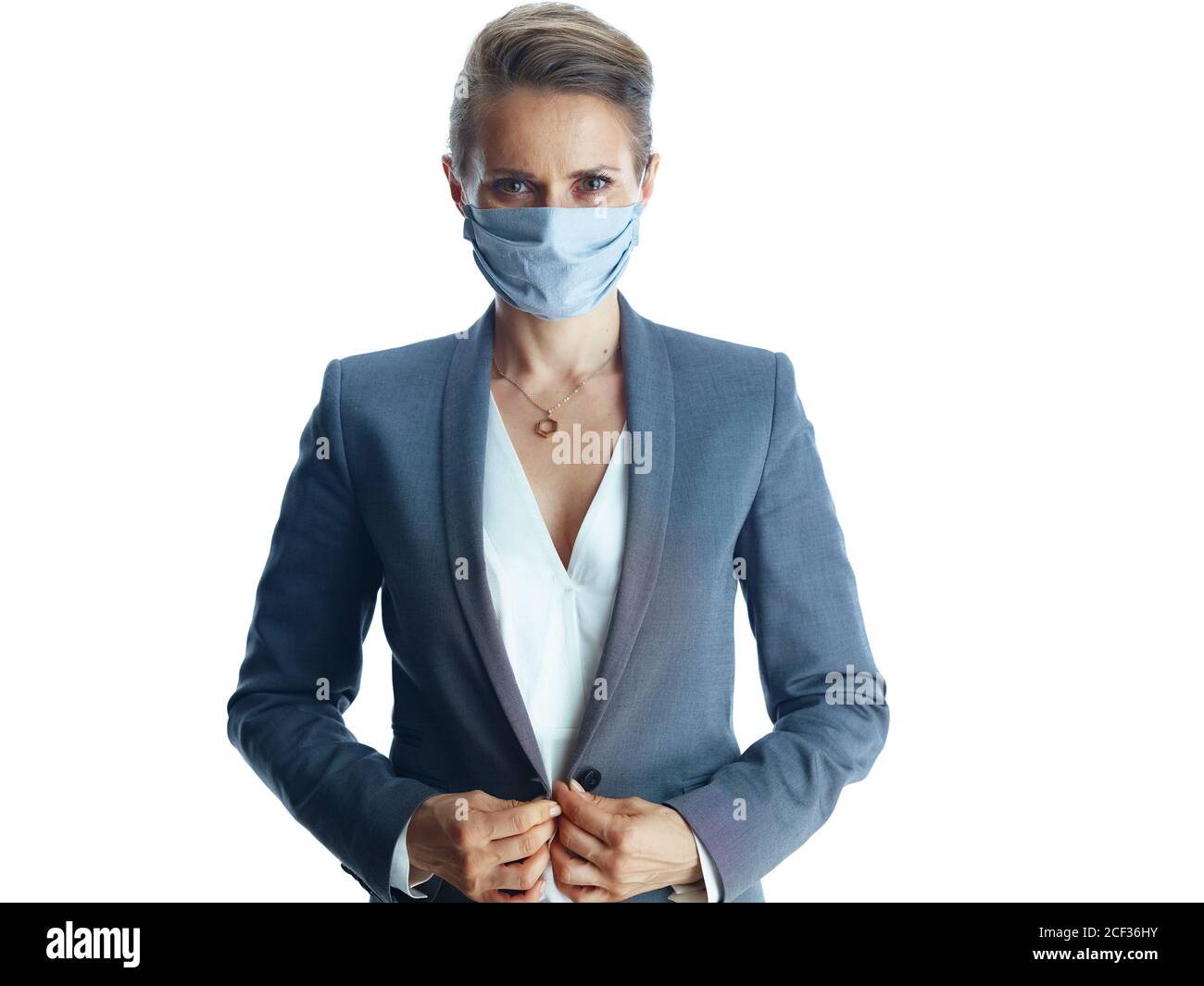 Geschäft während der covid-19 Pandemie. Porträt von selbstbewussten 40 Jahre alte Geschäftsfrau in einem grauen Anzug mit medizinischen Maske isoliert auf weißem Hintergrund. Stockfoto