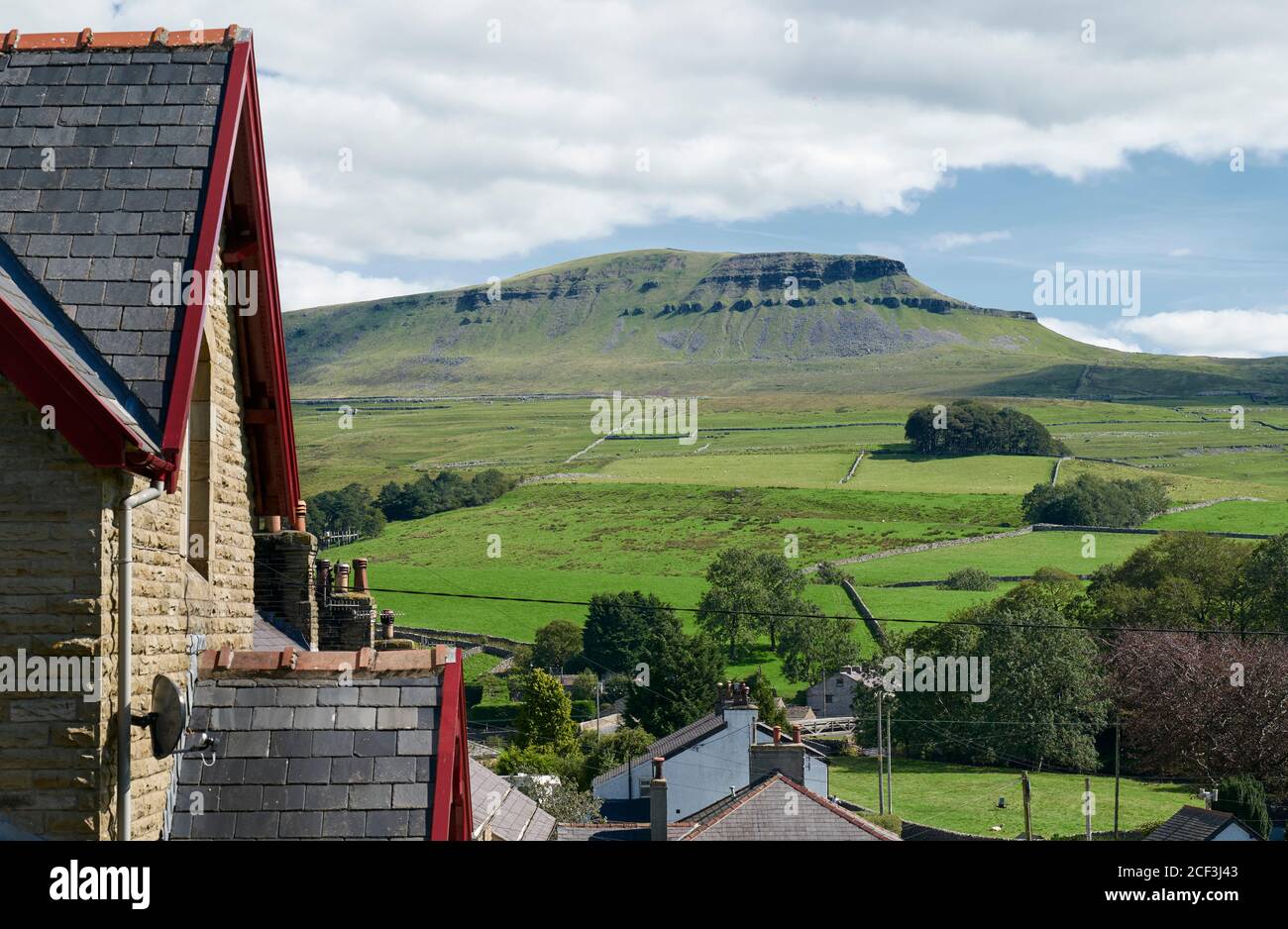 Steingebäude mit roten Dachrinnen in Horton im Dorf Ribblesdale Mit Pen-y-ghent Hügel steigt über Moor in der Ferne Stockfoto